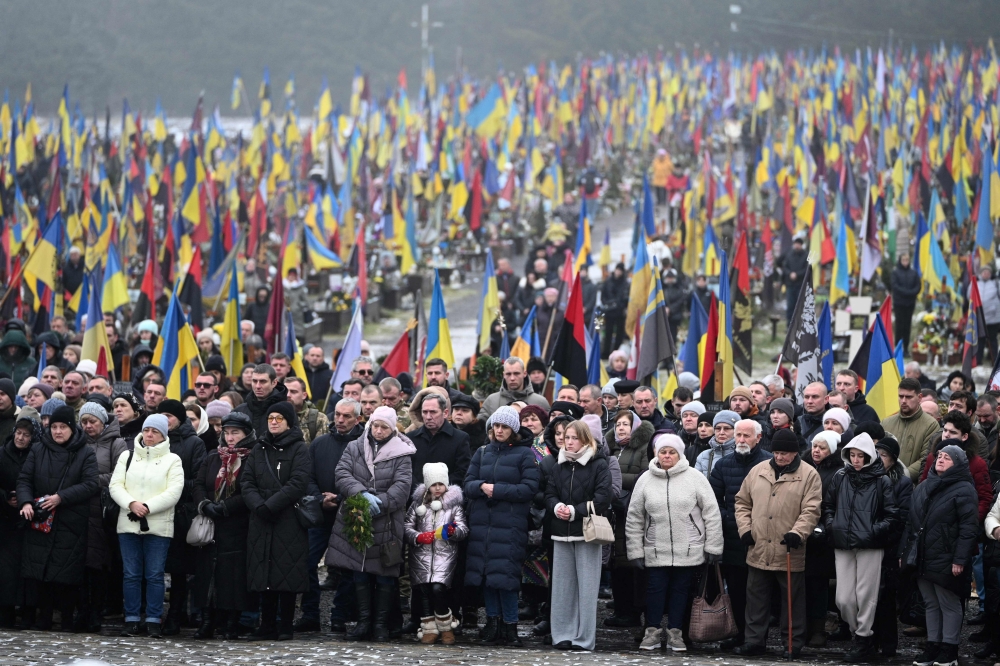 People stand during a memorial service at the Lychakiv Military Cemetery, in Lviv