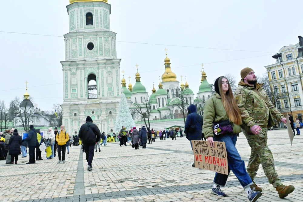 A woman walks with a serviceman as she holds a slogan which reads "Fight for them as they fought for us, Don't be silent" during a rally to call for the exchanges of Ukrainian prisoners of war, at St. Sophia Square in Kyiv. — AFP