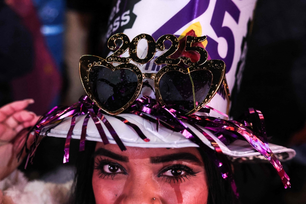A reveler looks on as people celebrate New Year's Eve in Times Square on December 31, 2024, in New York City. (Photo by Yuki IWAMURA / AFP)
