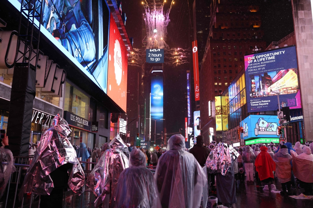 Revelers wear ponchos under the rain as they celebrate New Year's Eve in Times Square on December 31, 2024, in New York City. (Photo by Yuki IWAMURA / AFP)


