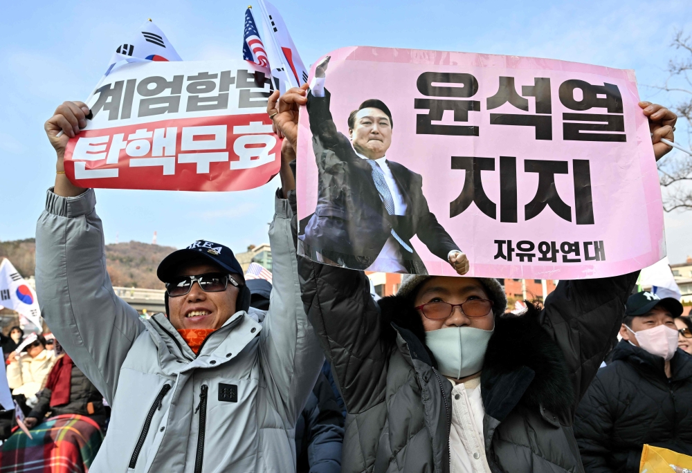 A supporter of impeached South Korea President Yoon Suk Yeol holds a placard showing a picture of the president as supporters gather near the presidential residence in Seoul. — AFP