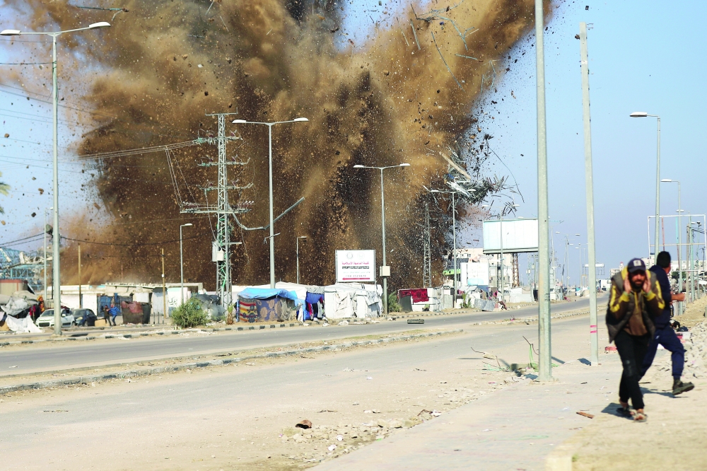 Palestinians take cover as sand and debris scatter following an Israeli strike, in Deir Al-Balah. — Reuters 