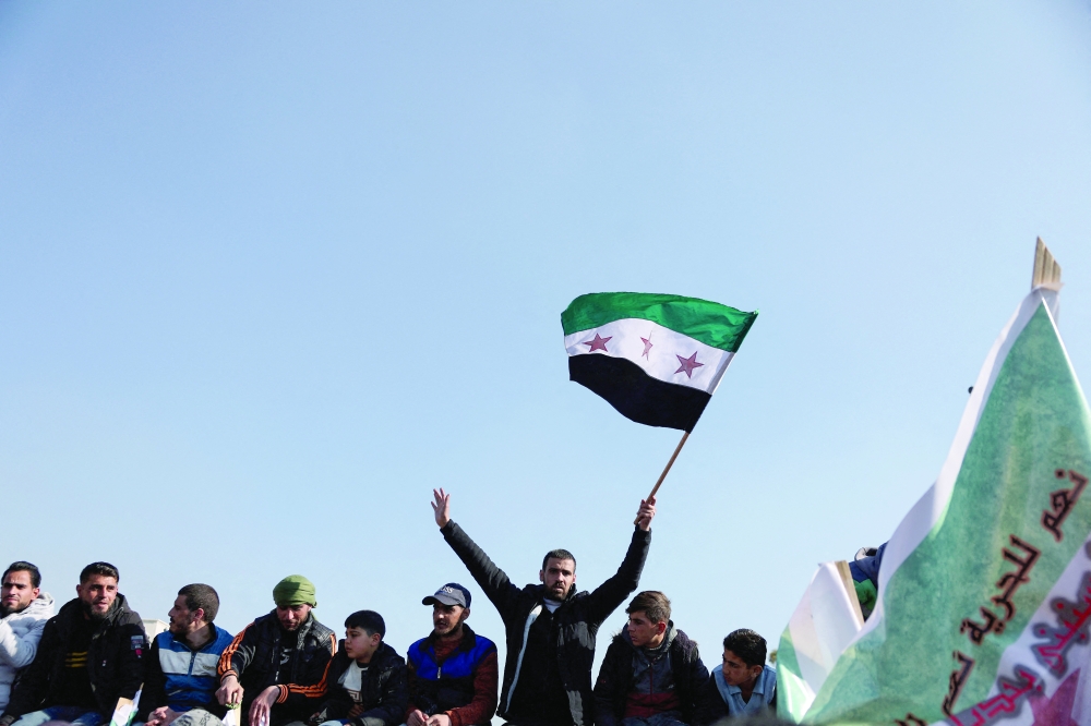 Syrians gather raising the country's flag, in Umayyad Square,in Damascus. — Reuters