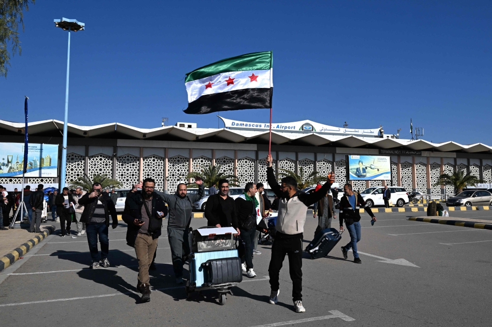 Travellers are welcomed as they exit the Damascus International Airport. — AFP 