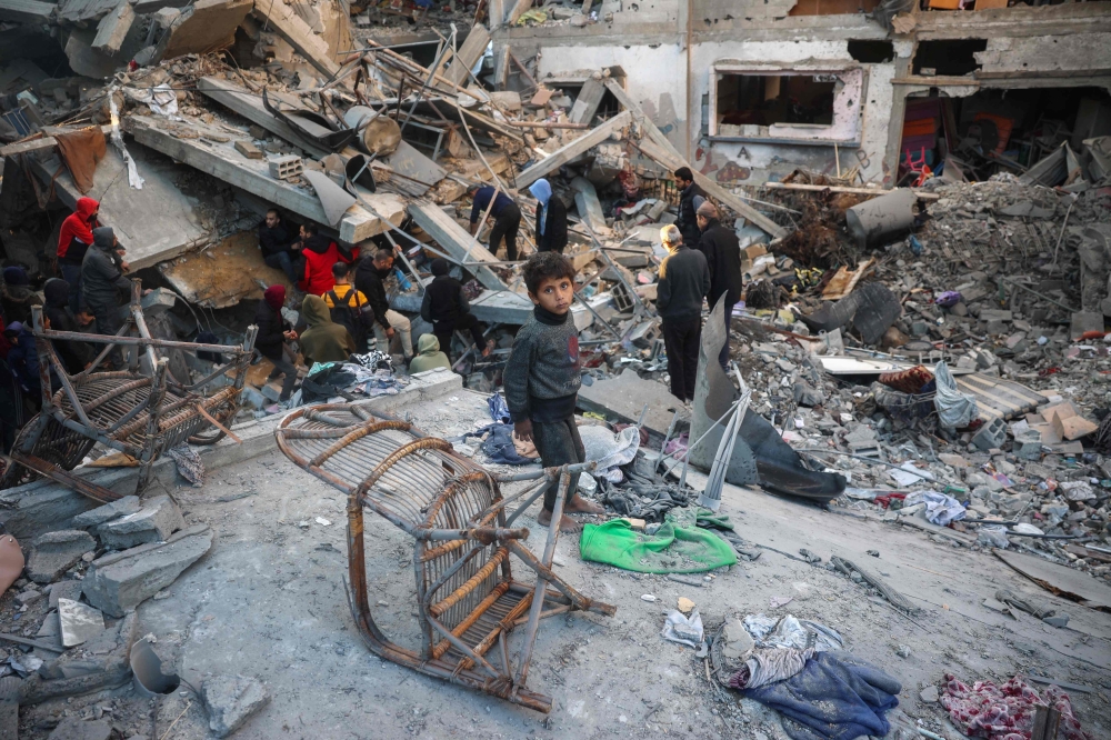 Palestinians search the rubble of a building destroyed in an Israeli strike on the Bureij camp, in central Gaza. — AFP 