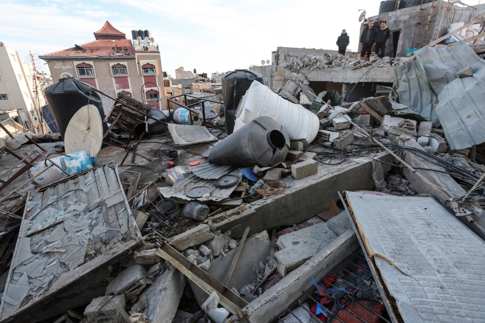 Palestinians inspect the site of an Israeli strike on a house in Nuseirat in the central Gaza Strip. - Reuters
