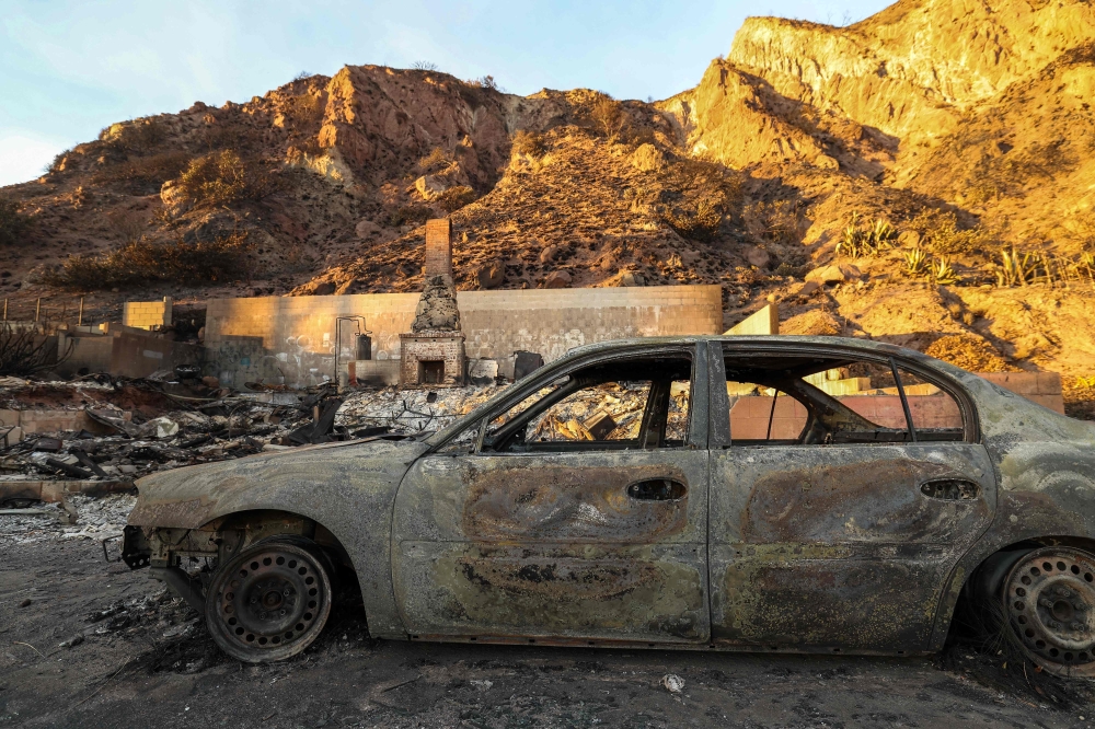 Scorched cars and burned-out homes destroyed by the Palisades Fire are seen along the Pacific Coast Highway in Malibu, California. - AFP
