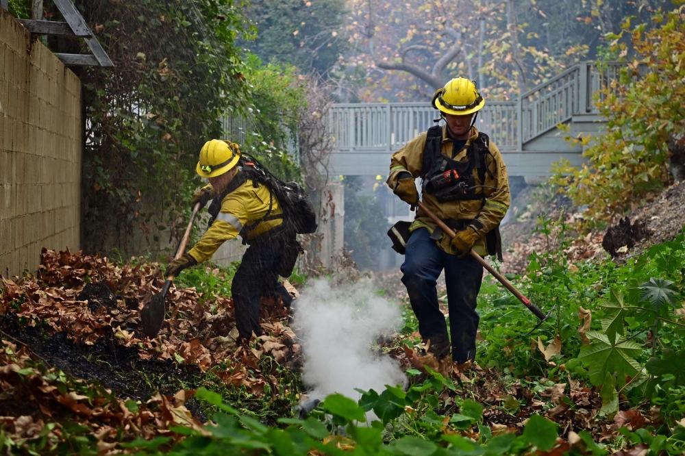 Firefighters puts out flames in the Mandeville Canyon neighbourhood of Los Angeles, California, on Sunday. - AFP