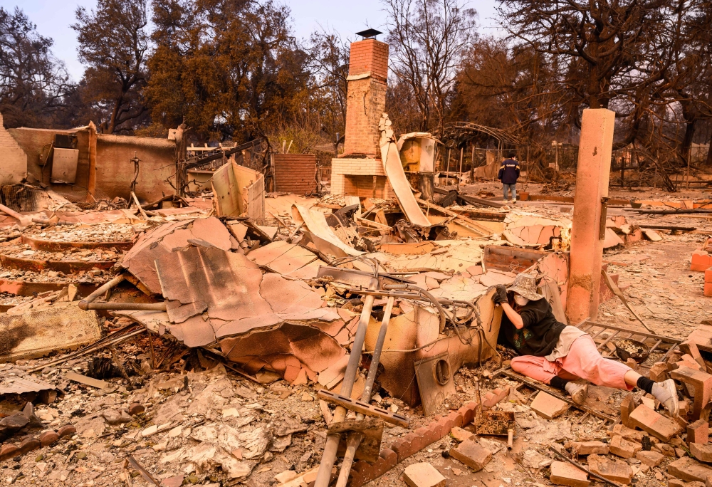 Alana Dadoorian searches through the remains of her burned home during the Eaton fire in the Altadena area of Los Angeles