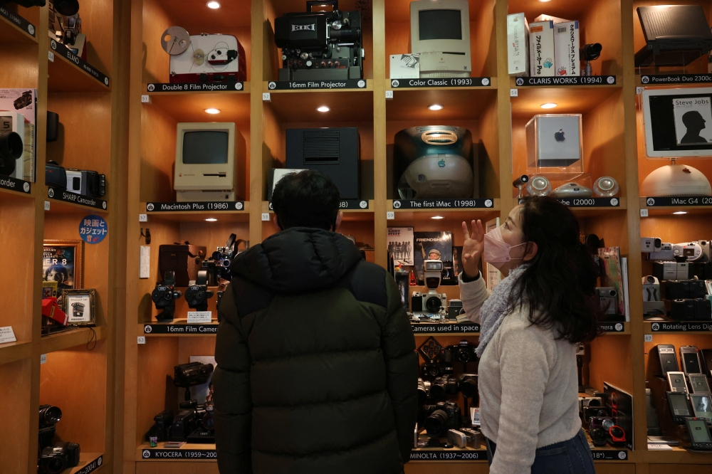 Visitors view items inside Extinct Media Museum, a private museum showcasing a collection of defunct gadgets including old cameras, cassette tapes and cell phone, in Tokyo, Japan January 11, 2025.  REUTERS/Irene Wang
