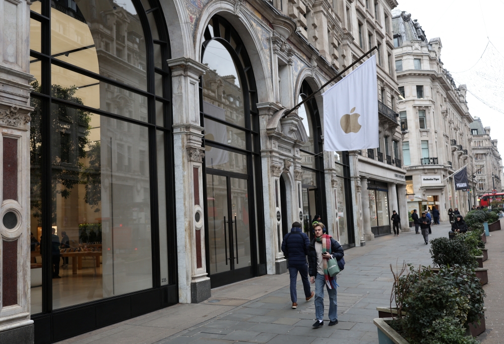 People walk past an Apple store in London. - Reuters