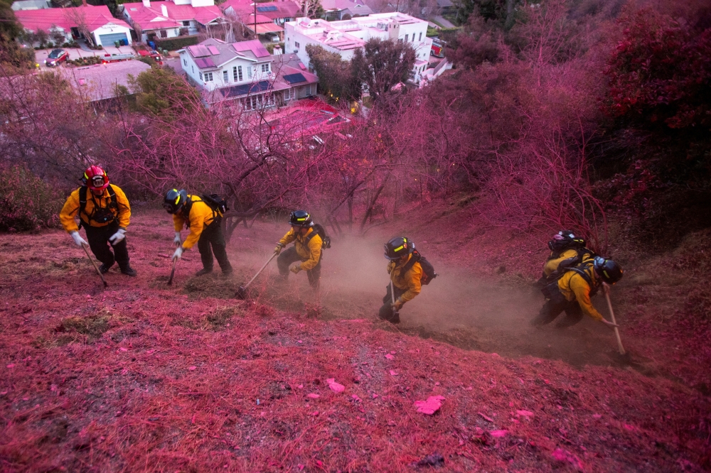 Firefighters work to clear a firebreak on a hillside covered with retardant as the Palisades Fire, burns in Mandeville Canyon, Los Angeles. — Reuters 