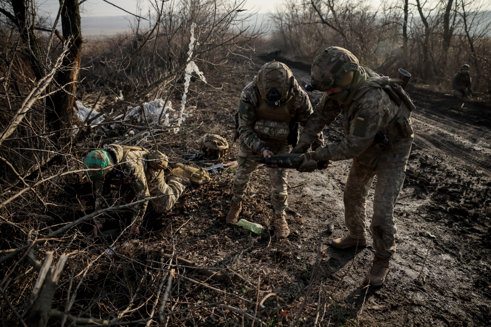 Sappers carry an unexploded shell as they inspect an area for mines near the town of Chasiv Yar in Donetsk region, Ukraine. — Reuters 