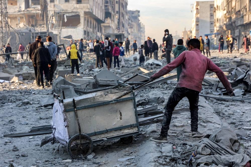 A boy pulls a cart loaded with salvaged items from the site of Israeli bombardment on a residential block in Jalaa Street in Gaza City. — AFP