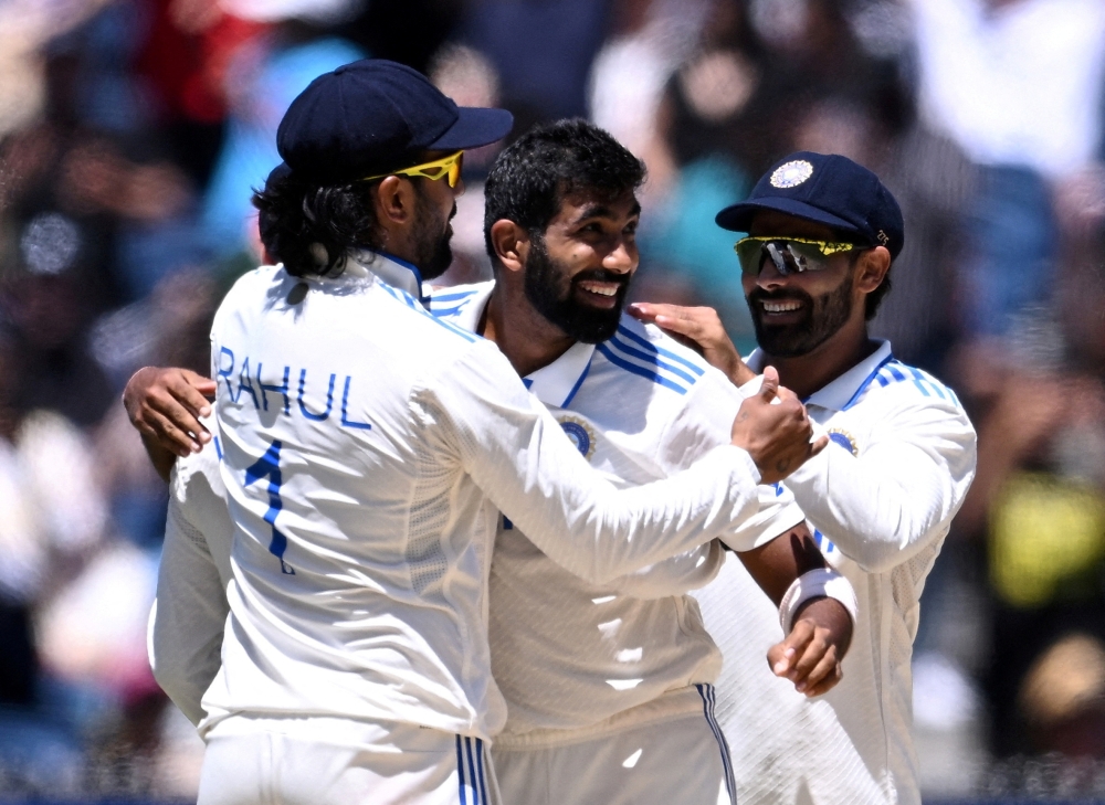 India's Jasprit Bumrah celebrates with KL Rahul and teammates after taking the wicket of Australia's Travis Head