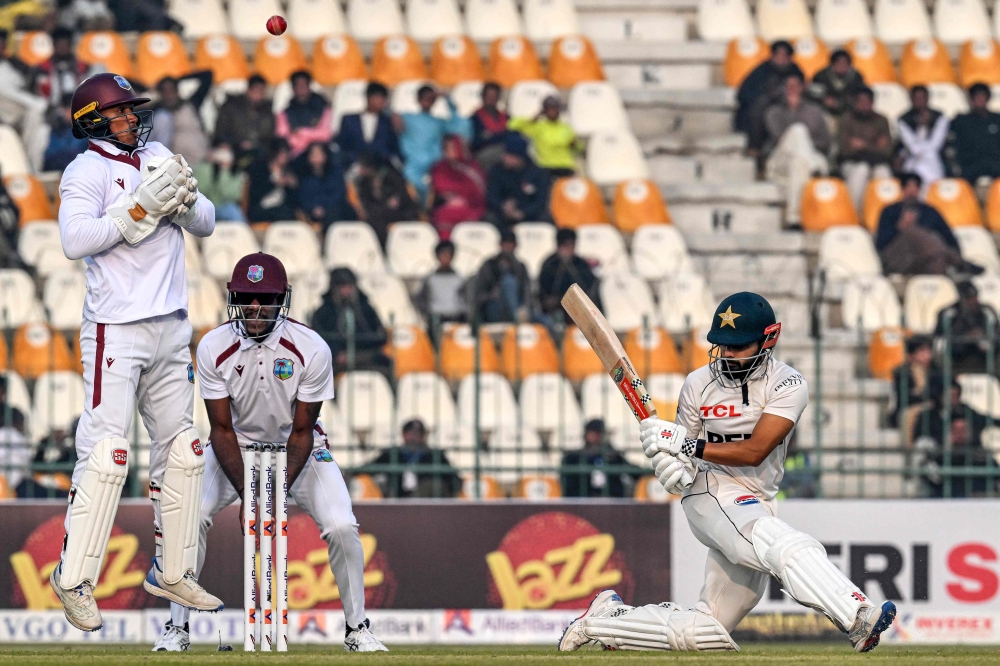Pakistan's Saud Shakeel (R) plays a shot as West Indies' Tevin Imlach (L) fields the ball during the first day of the first Test cricket match 
