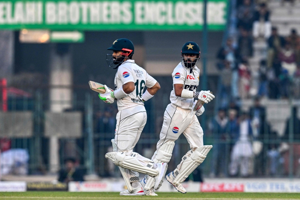Pakistan's Mohammad Rizwan (L) and Saud Shakeel run between the wickets during the first day of the first Test cricket match 