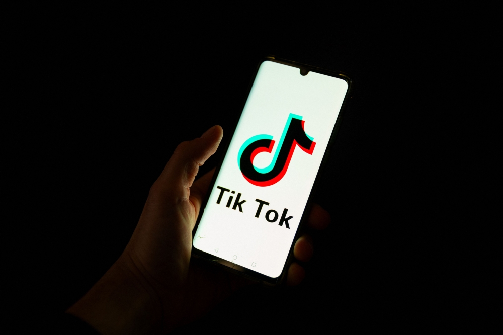 A man holding a smartphone displaying the logo of Chinese social media platform Tiktok in an office in Paris