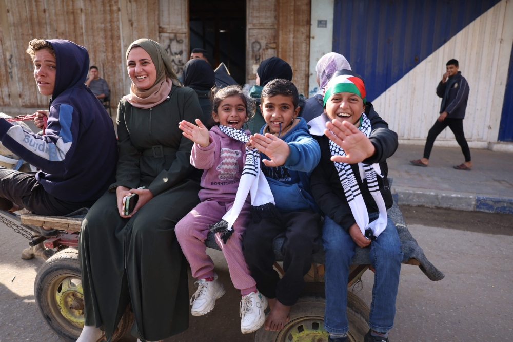Children cheer in Nuseirat in the central Gaza Strip on January 19, 2025, shortly before a ceasefire deal in the war between Israel and the Palestinian militant group Hamas was implemented.   (Photo by Bashar TALEB / AFP)
a

