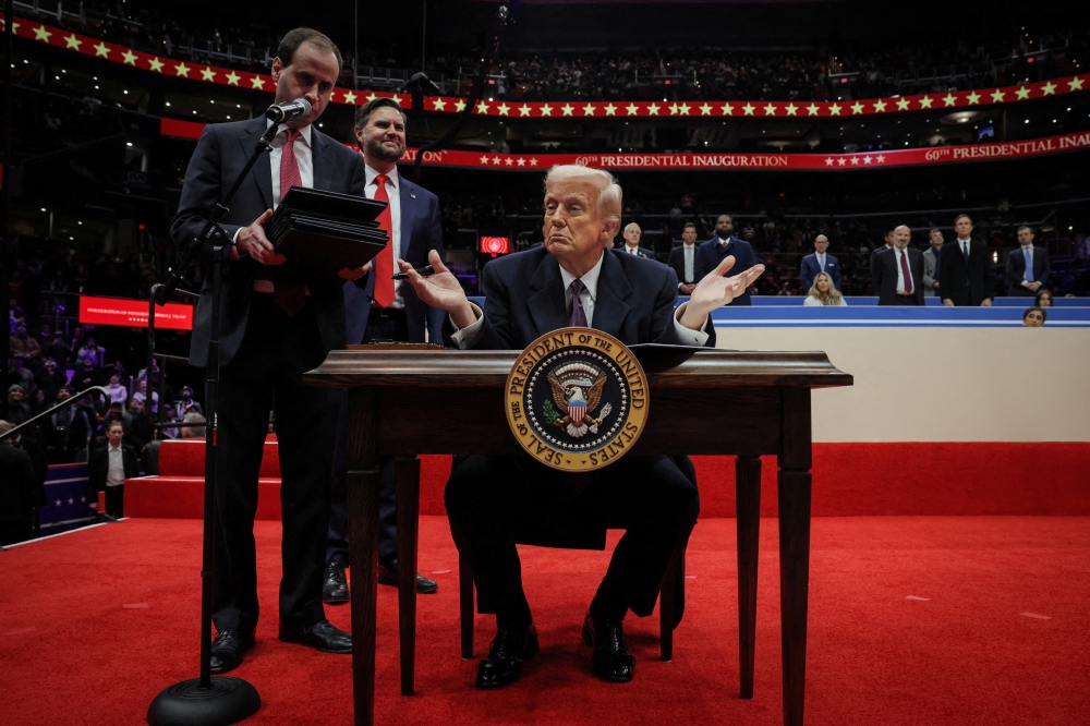 The US President Donald Trump gestures on the day he signs executive orders during the inaugural parade inside Capital One Arena on the inauguration day, in Washington. — Reuters 