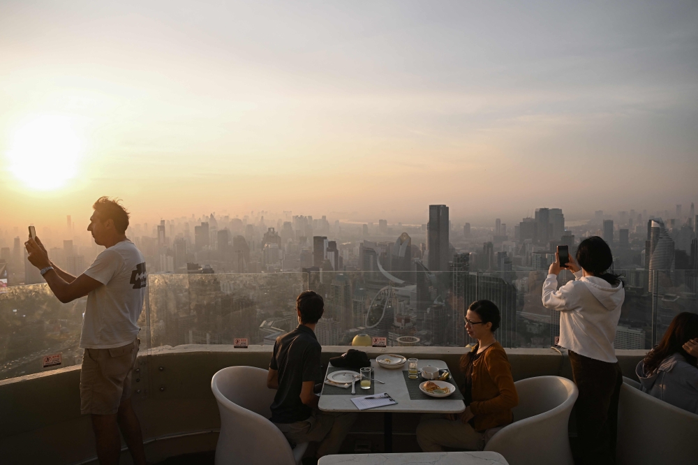 Tourists eat breakfast at a hotel skybox amidst high air pollution levels in Bangkok. - AFP

