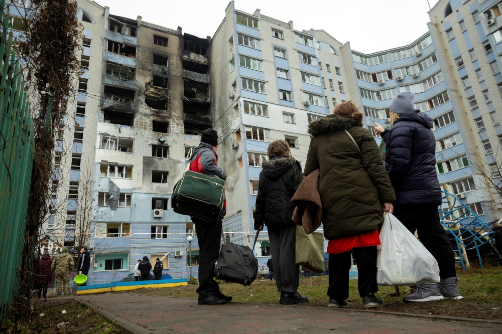 Residents look at their apartment building that was struck by a Russian drone