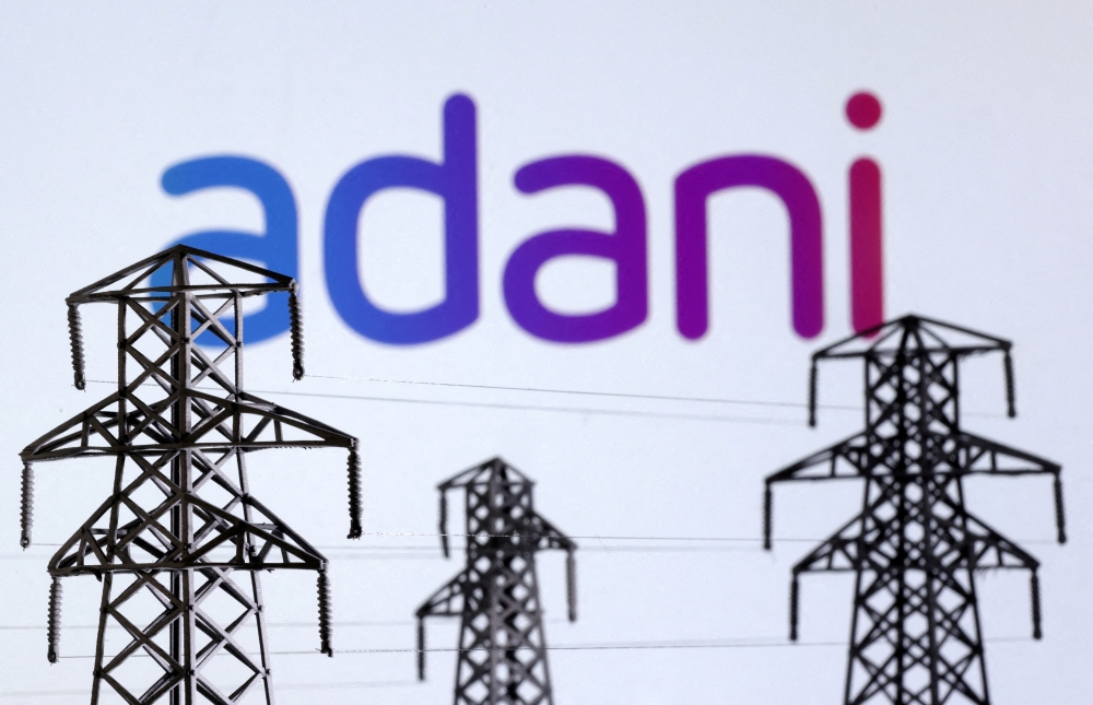 Electric power transmission pylon miniatures and Adani Green Energy logo seen in this illustration