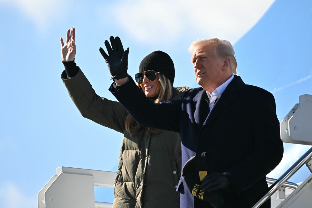 US President Donald Trump and Melania Trump wave as they steps off of Air Force One upon arrival at Asheville Regional Airport in Fletcher