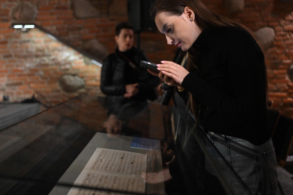 A woman uses a mobile phone to take a photo of a manuscript of the first and unpublished version of the Ballade in F minor, Op. 52 written by Polish composer Frederic Chopin, during its presentation at the Fryderyk Chopin Museum in Warsaw, Poland, on January 23, 2025. Poland announced it had purchased a rare manuscript of a ballad by Frederic Chopin, a score whose exhibition will coincide with this year's prestigious piano competition bearing the composer's name. The manuscript for Ballade No. 4 in F minor was previously in private hands before Poland finalised a deal to buy it. (Photo by Sergei GAPON / AFP)

