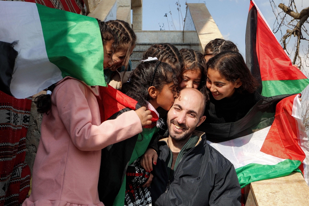 TOPSHOT - Ahmed Badie, a Palestinian former prisoner who spent 19 years in prison out of a 40-year-sentence and who was released by Israel, embraces his relatives' children as they greet him at their family home in Qalandia, south of Ramallah in the occupied West Bank on January 26, 2025. Palestinian militants and Israel carried out a hostage-prisoner swap on January 25 under the Gaza ceasefire deal, but a last-minute dispute blocked the expected return of hundreds of thousands of Palestinians to devastated northern Gaza. (Photo by Zain JAAFAR / AFP)
