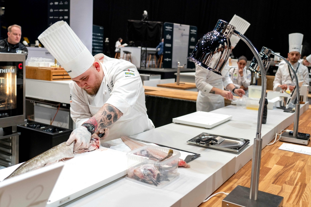 Picture taken on March 19, 2024 in Trondheim, Norway, shows Danish chef Sebastian Holberg Svendsgaard (L) preparing a fish during the European final in the Bocuse d'Or Europe competition in Trondheim Spektrum. Struggling at school but eager to compete, Danish chef Sebastian Holberg Svendsgaard is hoping to win the Bocuse d'Or in Lyon on Monday, January 27, 2025, the ultimate title in the culinary "Olympics". - Norway OUT
 (Photo by Gorm Kallestad / NTB / AFP)

