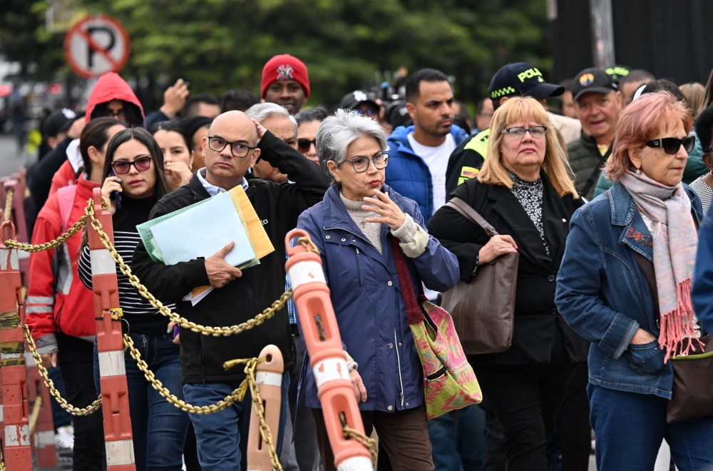 People wait outside the US embassy after their visa appointments were cancelled in Bogota. — AFP 