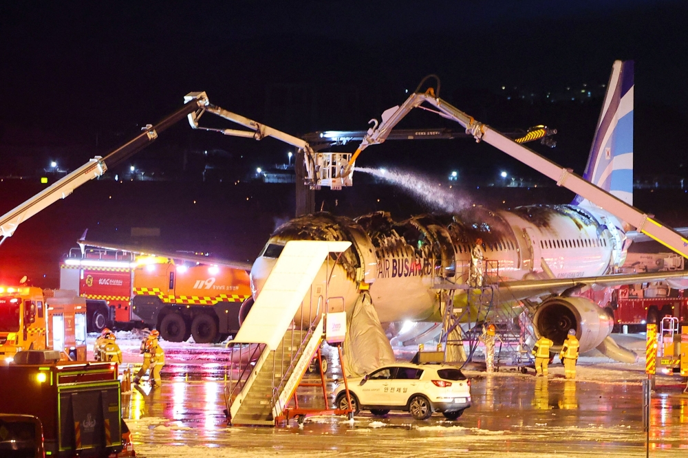Firefighters work to extinguish a fire that broke out on an Air Busan passenger plane bound for Hong Kong
