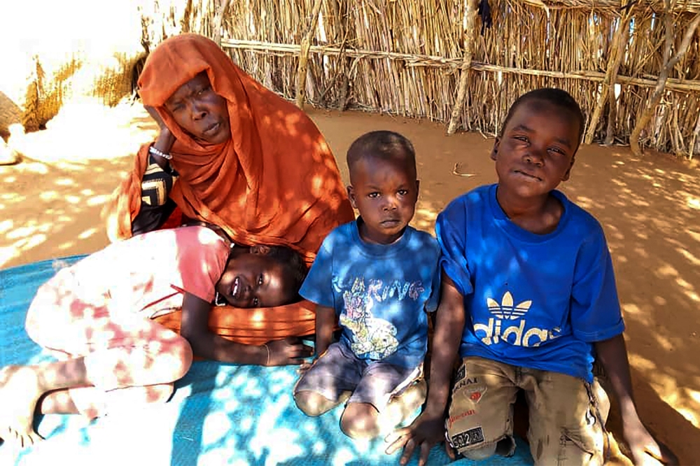 Displaced Sudanese mother Mona Ibrahim and her children sit on the ground in the famine-stricken Zamzam camp for Internally Displaced Persons (IDP) in northern Darfur 