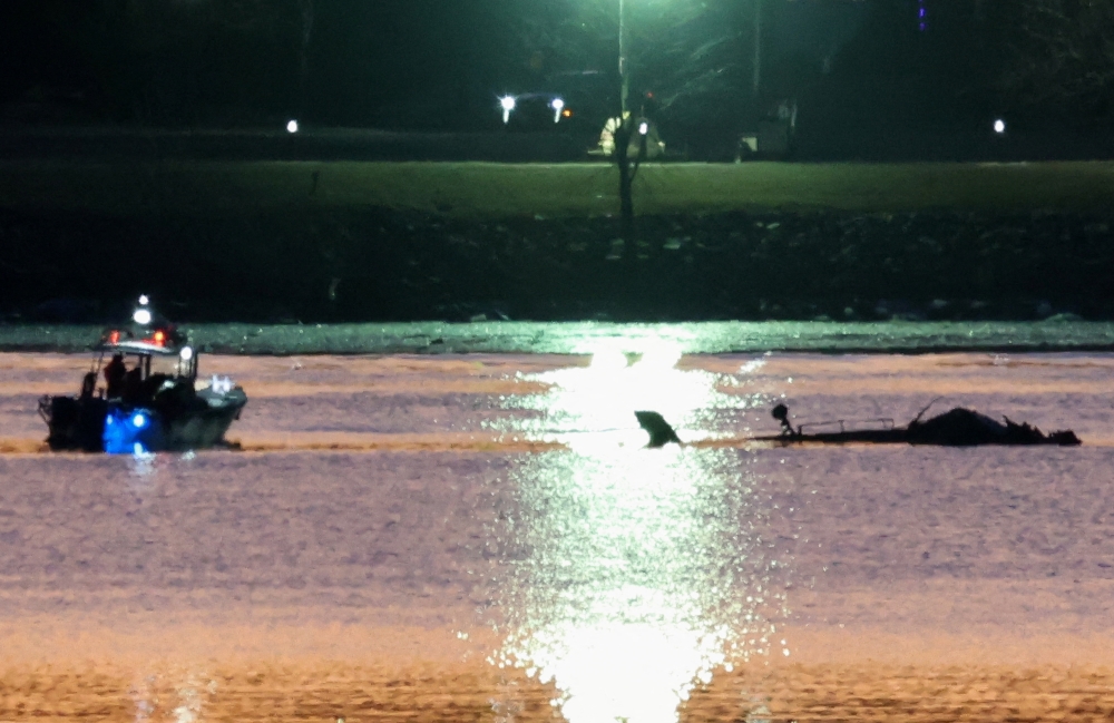 Rescuers on a boat work next to the wreckage of a Black Hawk helicopter at the site of the crash after it collided with the American Eagle flight 5342 which was approaching Reagan Washington National Airport and crashed into the Potomac River, outside Washington, U.S., January 30, 2025. REUTERS/Kevin Lamarque
