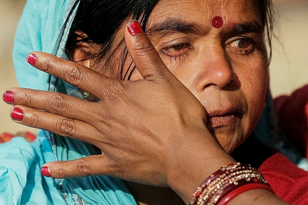 A pilgrim wipes the tears as they wait outside a mortuary to collect the body of her husband, who died in a stampede during the Maha Kumbh Mela festival in Prayagraj. - AFP