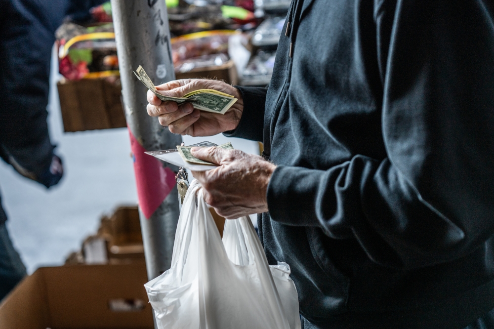 A vendor helps a customer with produce at a stand in Manhattan on Jan. 7, 2025. (Graham Dickie/The New York Times)
