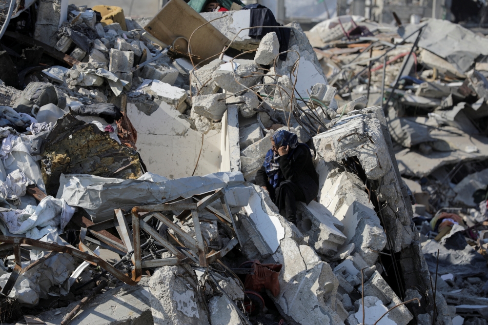 A Palestinian woman sits on the rubble of houses and buildings destroyed during the Israeli offensive in Jabalia refugee camp in the northern Gaza Strip
