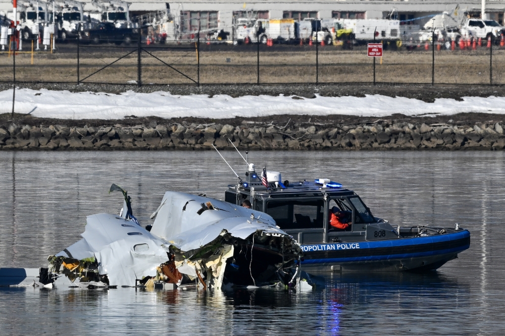 Emergency workers investigate the wreckage in the Potomac River as dawn breaks over Ronald Reagan Washington National Airport in Arlington, Va., on Thursday morning, Jan. 30, 2025. (Kenny Holston/The New York Times)