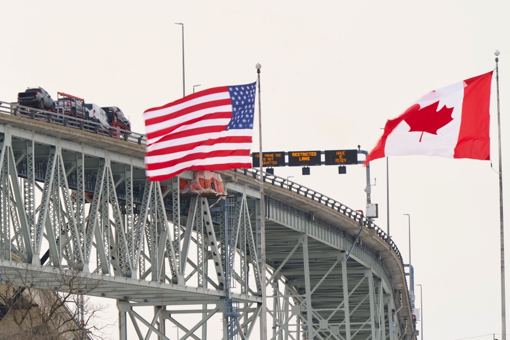  The US and Canadian flags fly on the US side of the St. Clair River near the Bluewater Bridge