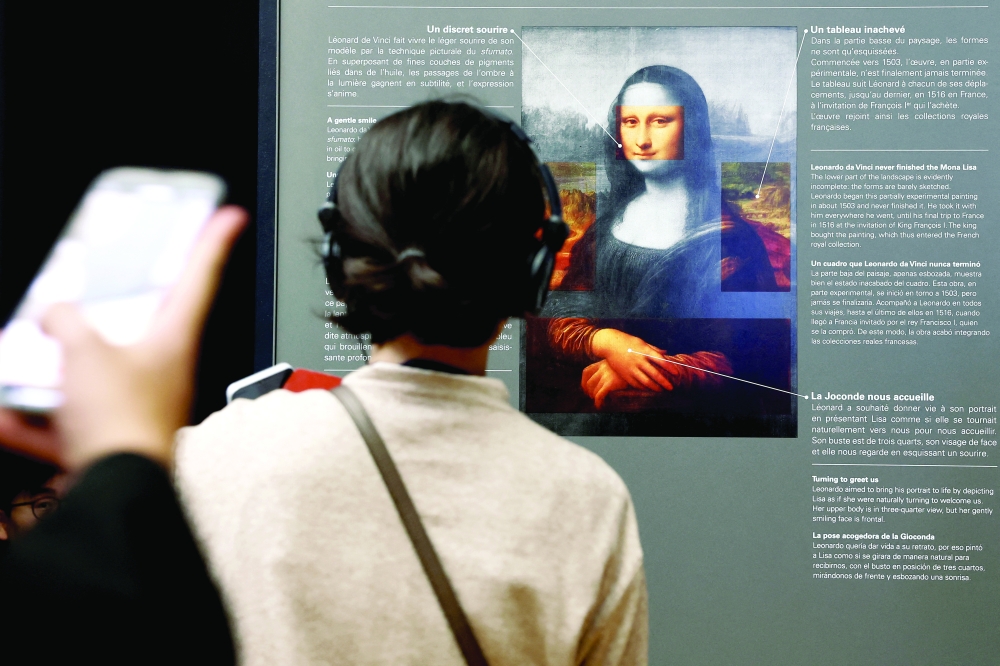 Visitors look at a sign with explanations about the painting "Mona Lisa" (La Joconde) by Leonardo da Vinci at the Louvre Museum in Paris, France, January 29, 2025. 
