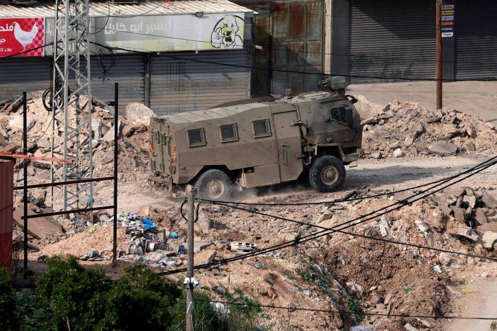 An Israeli military vehicles drives along a damaged street during a military raid in the al-Fara camp for Palestinian refugees