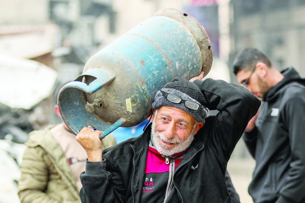 A Palestinian man carries a cooking gas cylinder, amid a ceasefire in Gaza City on Monday. — Reuters