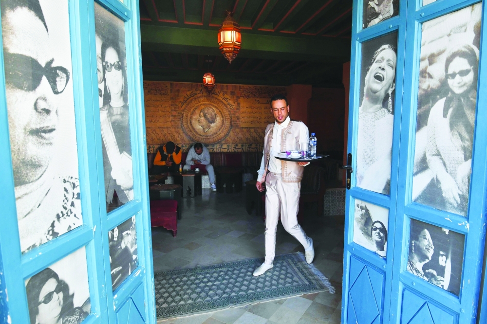 A waiter carries drinks at the Umm Kulthum cafe, named after the late Egyptian singer, songwriter and film actress, in the Tunisian tourist town of Hammamet on January 30, 2025. Umm Kulthum passed away in February 1975 but remains one of the most revered legends of music in the Arab world 50 years after her death. (Photo by FETHI BELAID / AFP)
