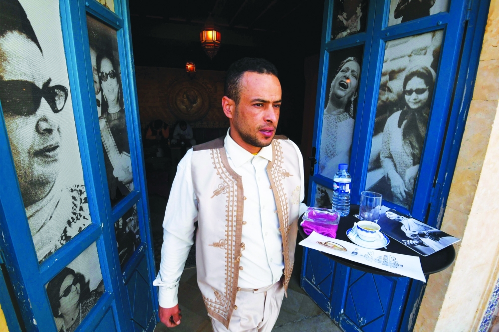 A waiter carries drinks at the Umm Kulthum cafe, named after the late Egyptian singer, songwriter and film actress, in the Tunisian tourist town of Hammamet on January 30, 2025. Umm Kulthum passed away in February 1975 but remains one of the most revered legends of music in the Arab world 50 years after her death. (Photo by FETHI BELAID / AFP)