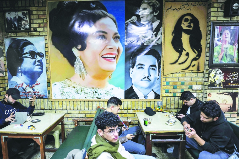 People sit at the Umm Kulthum cafe, which opened in 1970 and is named after the late Egyptian Arabic music icon Umm Kulthum, along al-Rashid Street in the old city of Baghdad on January 27, 2025.  (Photo by AHMAD AL-RUBAYE / AFP)