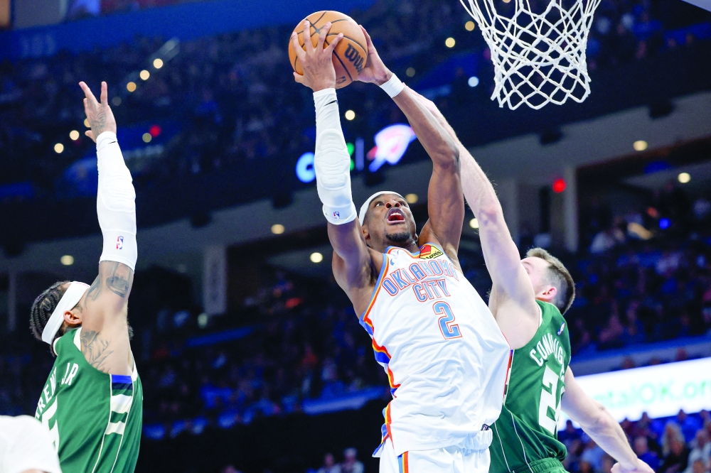 Oklahoma City Thunder's Shai Gilgeous-Alexander (2) goes up for a basket between Milwaukee Bucks' Gary Trent Jr (5) and Pat Connaughton (24) at Paycom Center. -- Imagn Images