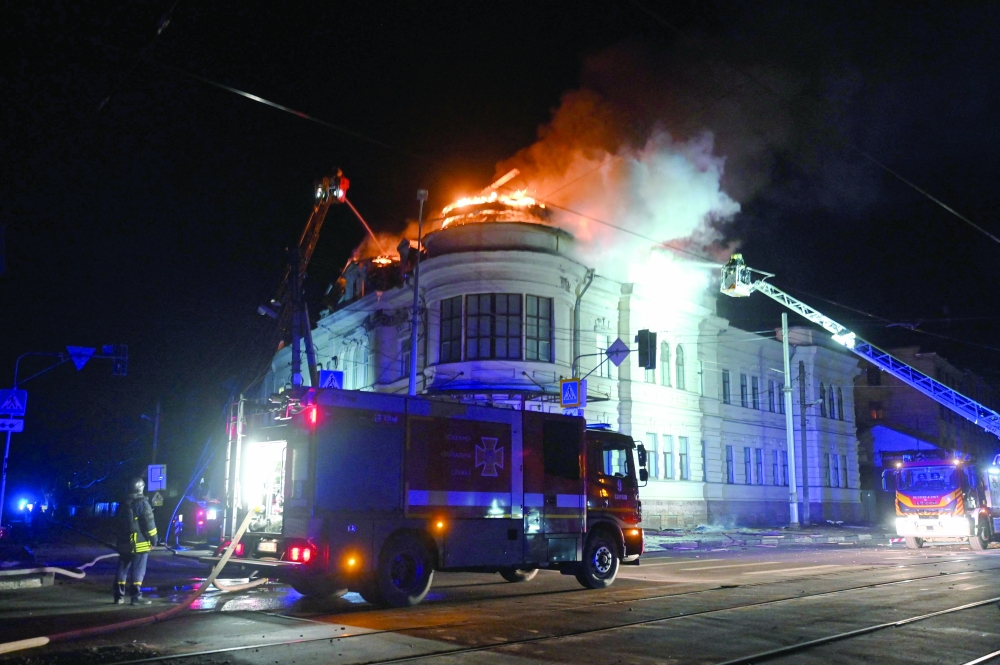 Ukrainian firefighters try to put out a fire in a building after a drone strike in Kharkiv. — AFP