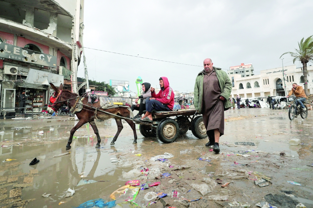 Palestinians make their way along a road on a rainy day, amid a ceasefire between Israel and Hamas in Gaza City. - Reuters