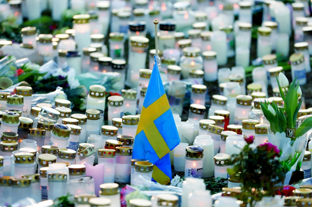 Candles, flowers and a Swedish flag are placed near the Risbergska school, following a deadly shooting attack at the adult education centre, in Orebro, Sweden. — Reuters